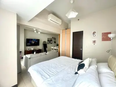 a bedroom with a large white bed and a couch at Cozy 1BR at Greenbelt Hamilton Makati in Manila