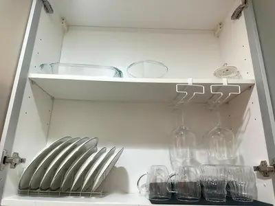 a shelf with glasses and wine glasses on it at Cozy 1BR at Greenbelt Hamilton Makati in Manila