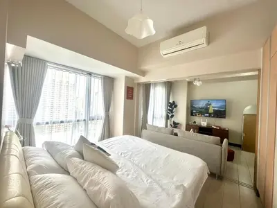a bedroom with a white bed and a large window at Cozy 1BR at Greenbelt Hamilton Makati in Manila