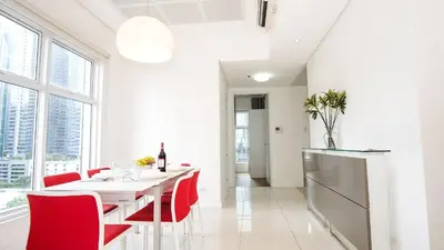 a white dining room with red chairs and a white table at Full-Serviced Residential Apartment in Uptown, BGC in Manila