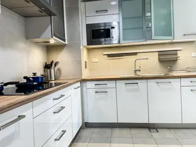 a kitchen with white cabinets and a sink and a microwave at Full-Serviced Residential Apartment in Uptown, BGC in Manila