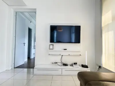 a living room with a tv on a white wall at Full-Serviced Residential Apartment in Uptown, BGC in Manila