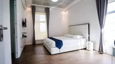 a white bedroom with a bed and a window at Full-Serviced Residential Apartment in Uptown, BGC in Manila