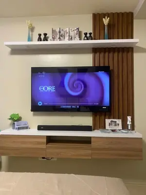 a flat screen tv sitting on top of a wooden entertainment center at Cozy studio unit 10mins from Airport 20mins from US Embassy across SM Sucat in Manila