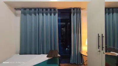 a bedroom with blue curtains and a bed and a table at Air Residence Tower B RM 445 Elegant and cosy Makati condoxd in Manila