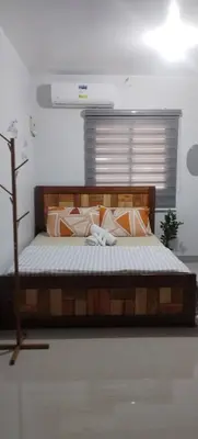 a bedroom with a wooden bed with pillows at Rosie's Staycation in Trece Martires, Cavite in Quintana