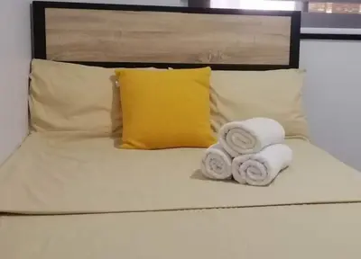 a bed with two towels and a yellow pillow at Rosie's Staycation in Trece Martires, Cavite in Quintana