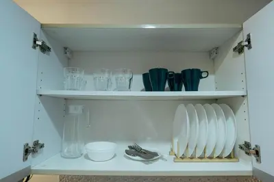 a cupboard with plates and glasses and utensils at Modern Living 5 with Fast Wifi and Netflix in Manila