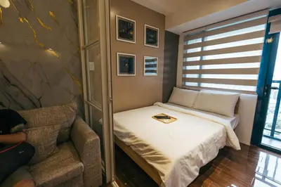 a small bedroom with a bed and a chair at Modern Living 5 with Fast Wifi and Netflix in Manila