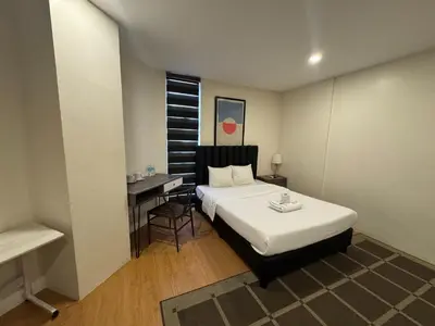 a bedroom with a bed and a desk and a table at The Circuit Manor Hotel near Ayala Malls Circuit in Manila