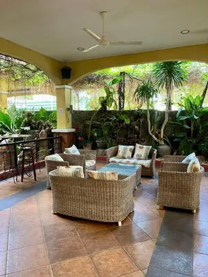 a room with wicker chairs and tables and a patio at Casa Verde Hotel & Events Center in Imus
