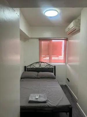 a bedroom with a bed in a room with a window at Ladybyugs Condotel Rental in Manila