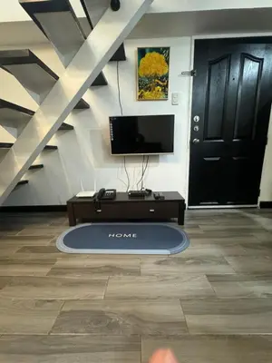 a living room with a tv and a black door at Ladybyugs Condotel Rental in Manila