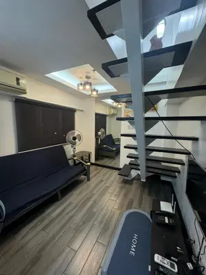 a living room with a couch and stairs in a building at Ladybyugs Condotel Rental in Manila