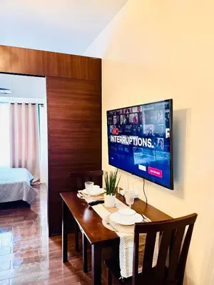 a dining room with a table and a tv on a wall at Makati City Oasis The Air Residences #2148 in Manila