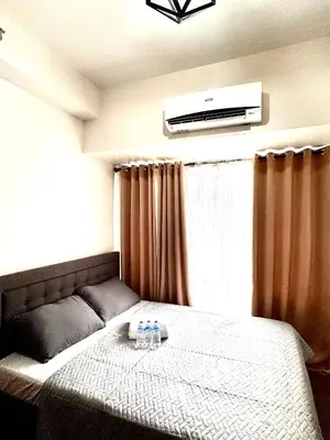 a bedroom with a bed with a television on the wall at Makati City Oasis The Air Residences #2148 in Manila