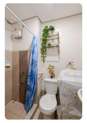 a small bathroom with a toilet and a shower at Benjamin's crib staycation in Manila
