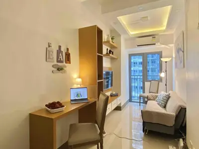 a living room with a desk with a laptop on it at Sleek 1 BR APT at FAME Residences with Balcony in Manila