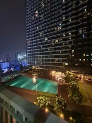 a large building with a swimming pool at night at Sleek 1 BR APT at FAME Residences with Balcony in Manila