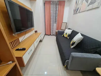 a living room with a couch and a flat screen tv at Sleek 1 BR APT at FAME Residences with Balcony in Manila