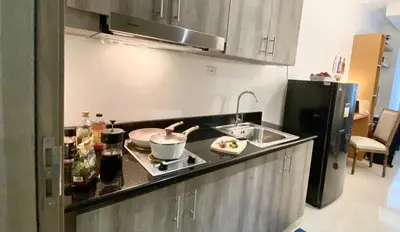 a kitchen with a sink and a stove top oven at Sleek 1 BR APT at FAME Residences with Balcony in Manila