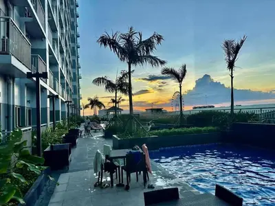 a resort pool with a table and chairs and palm trees at ck staycation coast residence in Manila