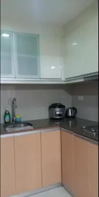 a kitchen with white cabinets and a sink and a stove at JRM Staycation Naia T3 in Manila