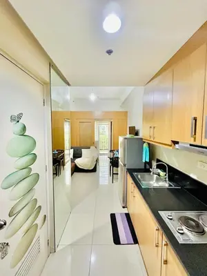 a kitchen with a sink and a living room at 1Bedroom Pool View - MOA Shell Residences Near Airport in Manila