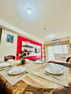 a living room with a table and a red wall at SGG Place 2 Bedroom Shell Residences Mall of Asia Near NAIA in Manila