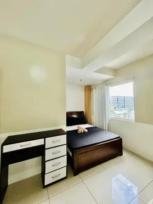 a bedroom with a bed with a desk and a window at SGG Place 2 Bedroom Shell Residences Mall of Asia Near NAIA in Manila