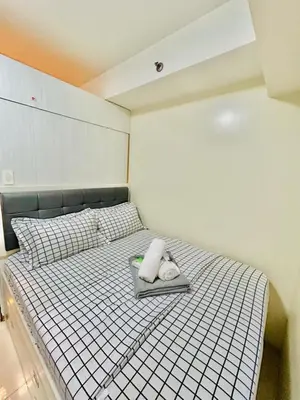 a bed with a tray with two towels on it at SGG Place Deluxe Room- MOA Shell Residences Near NAIA in Manila