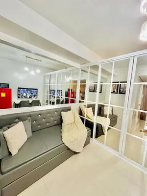 a living room with a gray couch and mirrors at SGG Place Deluxe Room- MOA Shell Residences Near NAIA in Manila