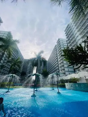 a fountain in a swimming pool in front of buildings at SGG Place Deluxe Room- MOA Shell Residences Near NAIA in Manila