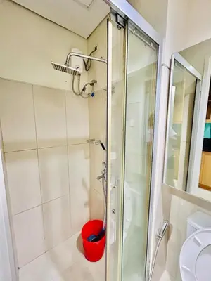 a shower with a red bucket in a bathroom at SGG Suite Room Pool View - Shell Residences MOA Pasay Near NAIA in Manila