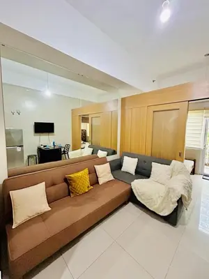 a living room with a brown couch with pillows at SGG Suite Room Pool View - Shell Residences MOA Pasay Near NAIA in Manila