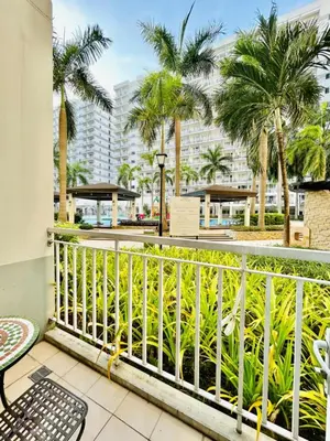 a balcony with a white railing and palm trees at SGG Suite Room Pool View - Shell Residences MOA Pasay Near NAIA in Manila