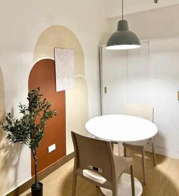 a dining room with a table and a white table and chairs at Meraki Stays - ETANA - SMDC Hope Residences in Trece Martires