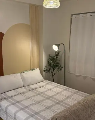 a bed in a room with a lamp and a plant at Meraki Stays - ETANA - SMDC Hope Residences in Trece Martires