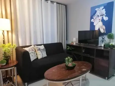 a living room with a black couch and a table at Royale 2BR Condo unit with free WiFi in Imus