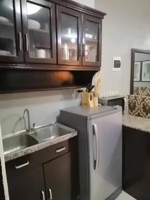 a kitchen with a stainless steel sink and wooden cabinets at Royale 2BR Condo unit with free WiFi in Imus