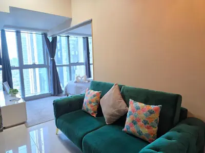 a green couch with pillows in a living room at BGC Cosy Nest Uptown Parksuites Tower 1 Near Nice Restaurants and Malls in Manila