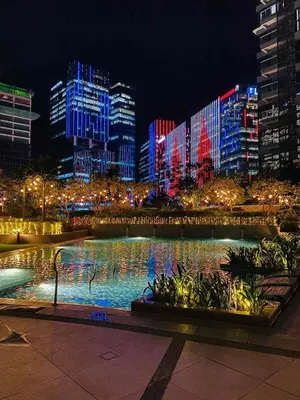 a city at night with illuminated buildings and a fountain at BGC Cosy Nest Uptown Parksuites Tower 1 Near Nice Restaurants and Malls in Manila