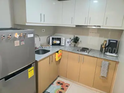 a small kitchen with a sink and a refrigerator at BGC Cosy Nest Uptown Parksuites Tower 1 Near Nice Restaurants and Malls in Manila