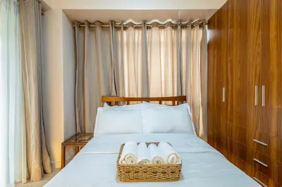 a bedroom with a bed with a basket of towels at 2br Forbeswood Heights in BGC near St Lukes in Manila