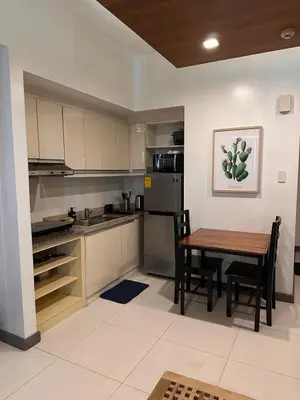 a kitchen with a wooden table and a table and chairs at Cozi Makati Executive Studio balcony in Manila