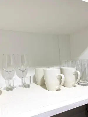 a shelf with cups and glasses on a counter at The Hive Staycation - SMDC Hope Residences in Trece Martires