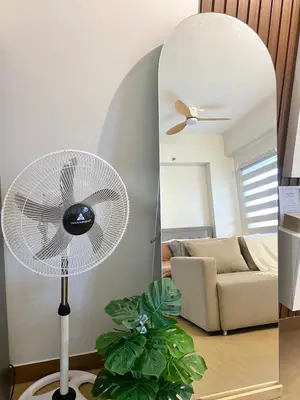 a white fan in a living room with a mirror at The Hive Staycation - SMDC Hope Residences in Trece Martires