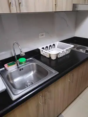 a kitchen counter with a sink and a dish rack at Shore Residence Tower III in Manila