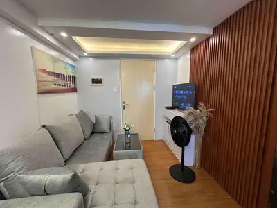 a living room with a couch and a tv at Cozy RC 2BR w loft Netflix Prime KTV Games in Manila