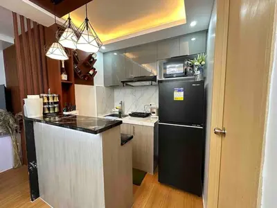 a kitchen with a black refrigerator and a counter at Cozy RC 2BR w loft Netflix Prime KTV Games in Manila